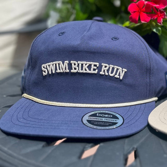 Two hats with text on a table outdoors with flowers in the background