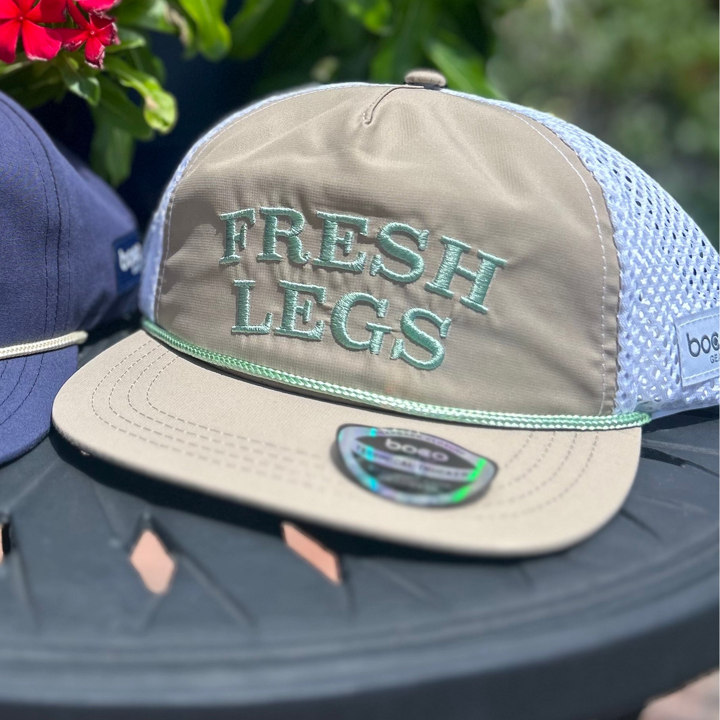 Two hats with text on a table outdoors with flowers in the background