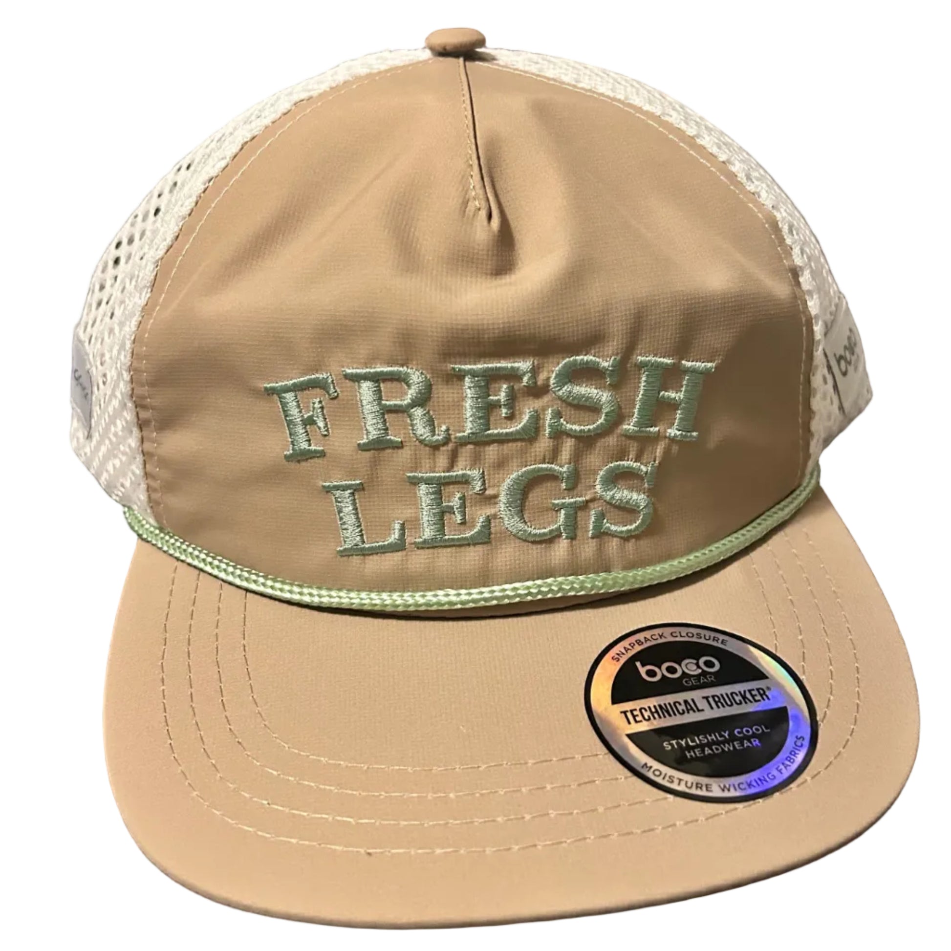 Beige cap with 'Fresh Legs' embroidery on a desk