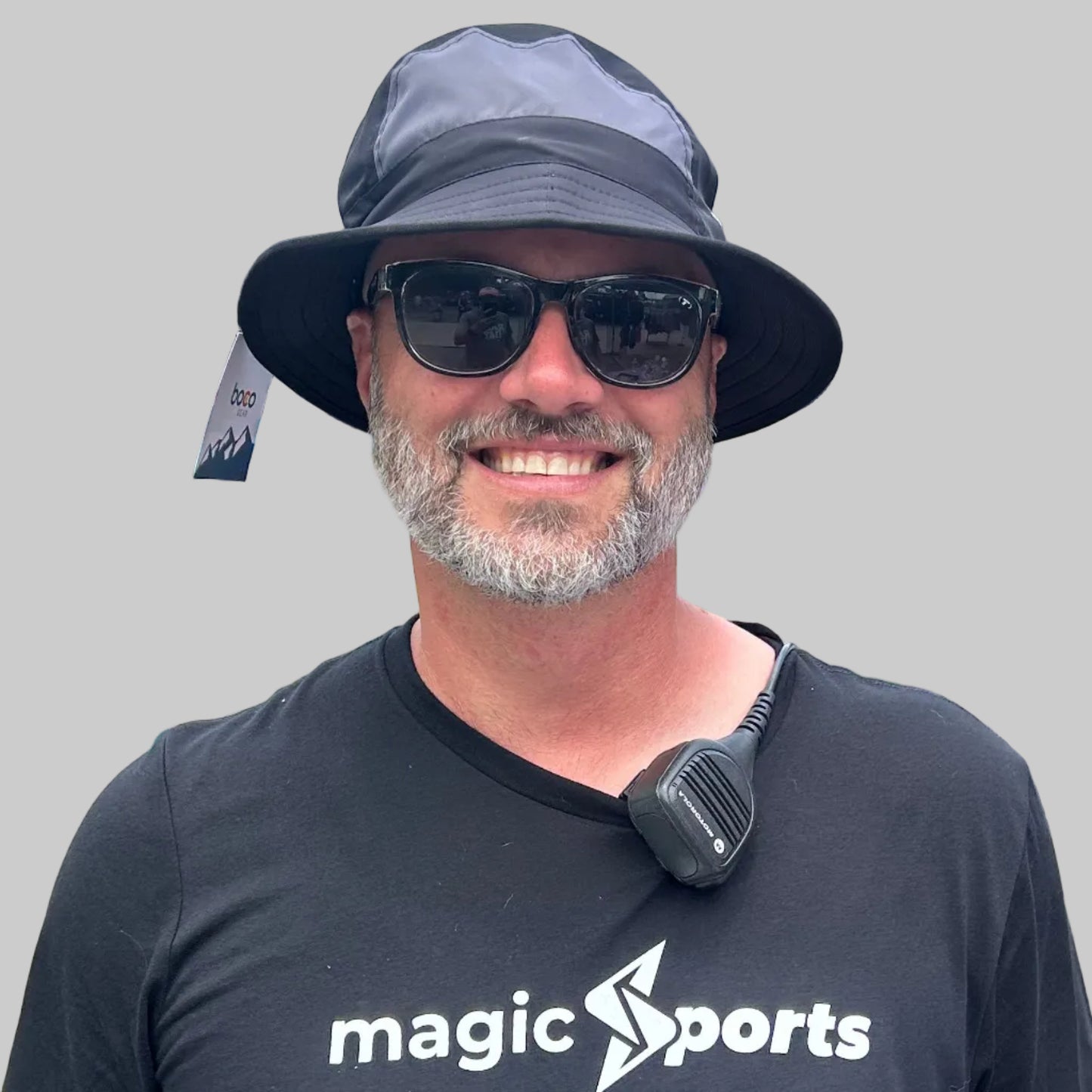 Man wearing a black 'magic sports' t-shirt with outdoor event background