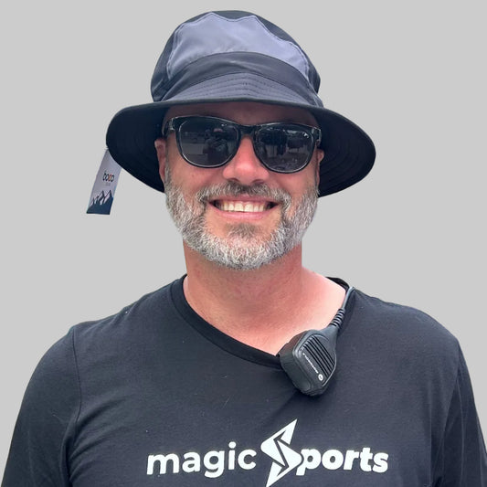 Man wearing a black 'magic sports' t-shirt with outdoor event background